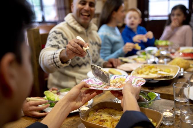 Family members pass dishes around a dinner table. Open larger view.