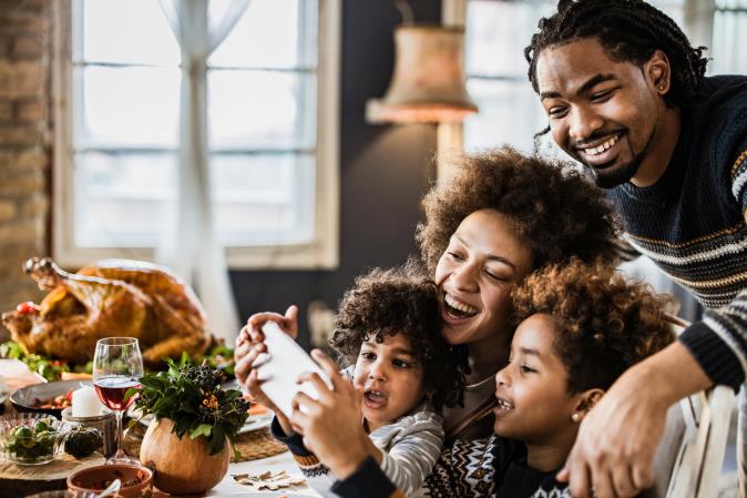 A family looks at a phone together beside a roast turkey. Open larger view.