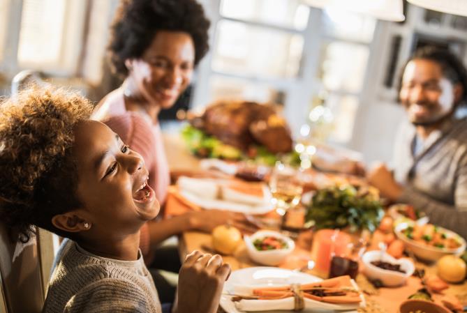 A boy laughs at a table full of holiday food. Open larger view.