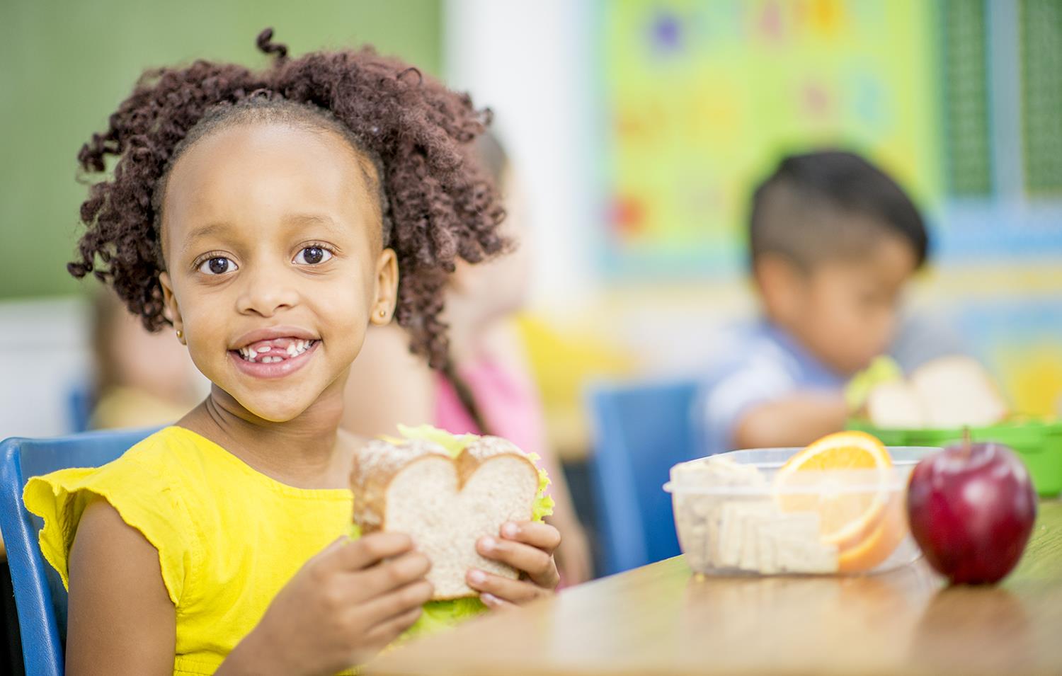 A smiling girl holds a sandwich